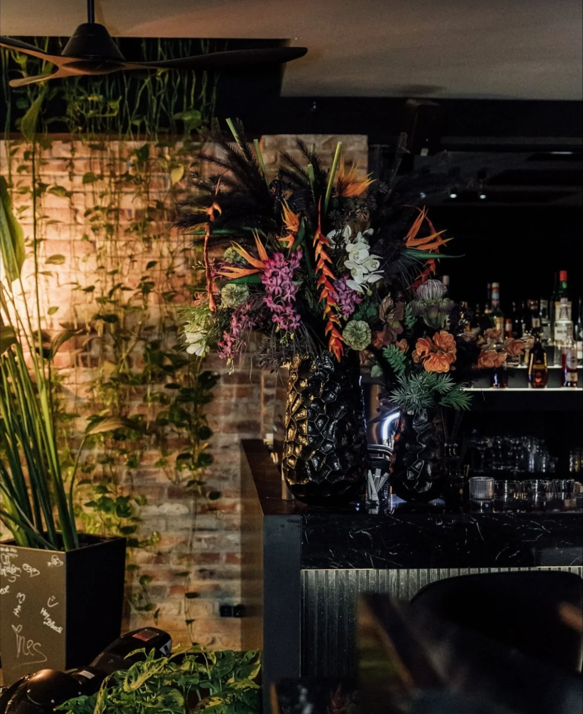Barecke im IVY mit Blumenarrangement und grüner Wand